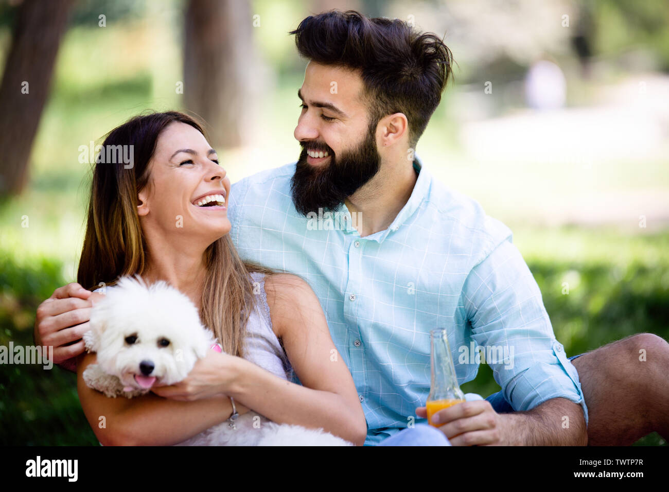 Lifestyle, happy couple resting at a picnic in the park with a dog ...