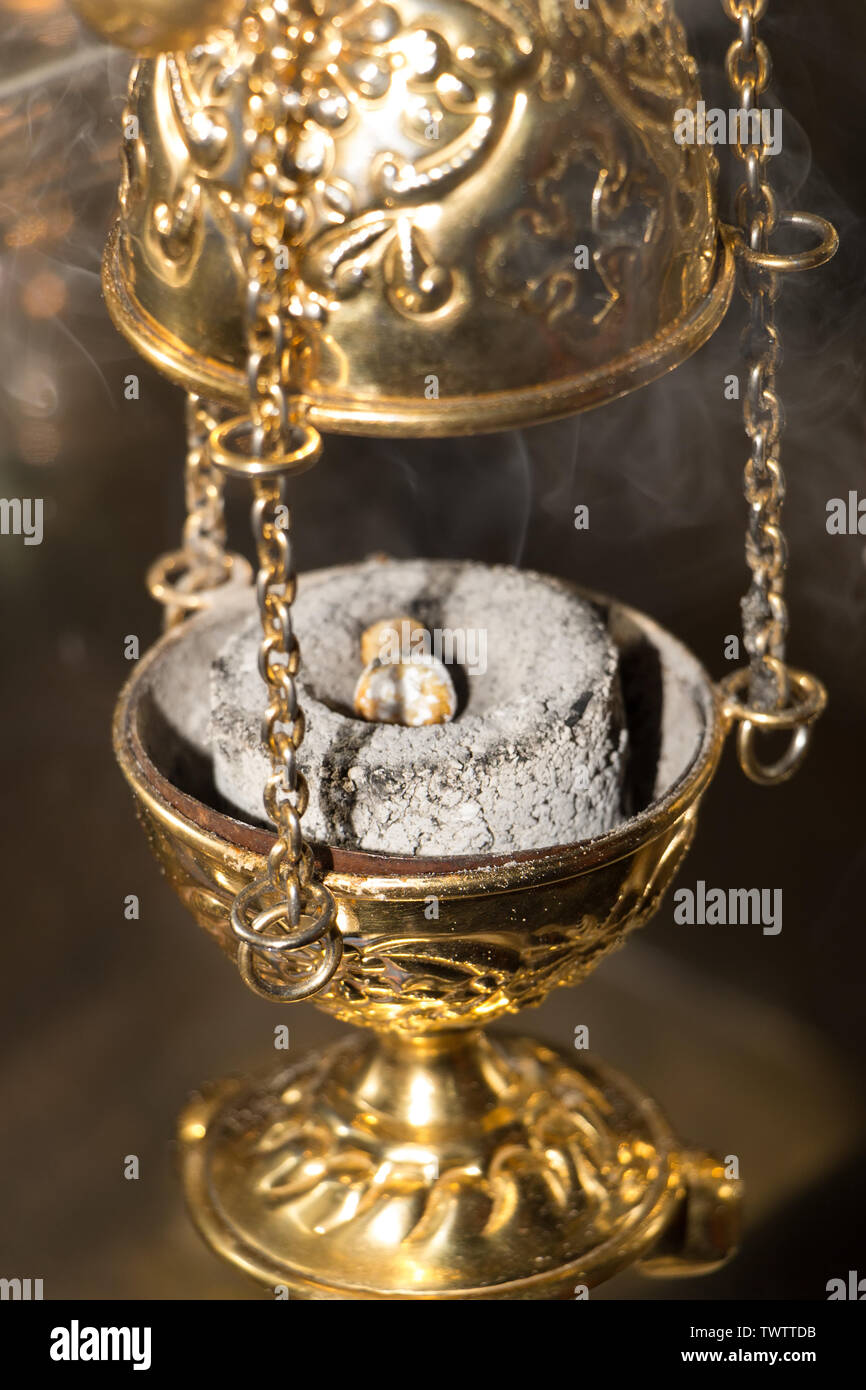 Worship service concept. Incense on burning coal tablet in golden