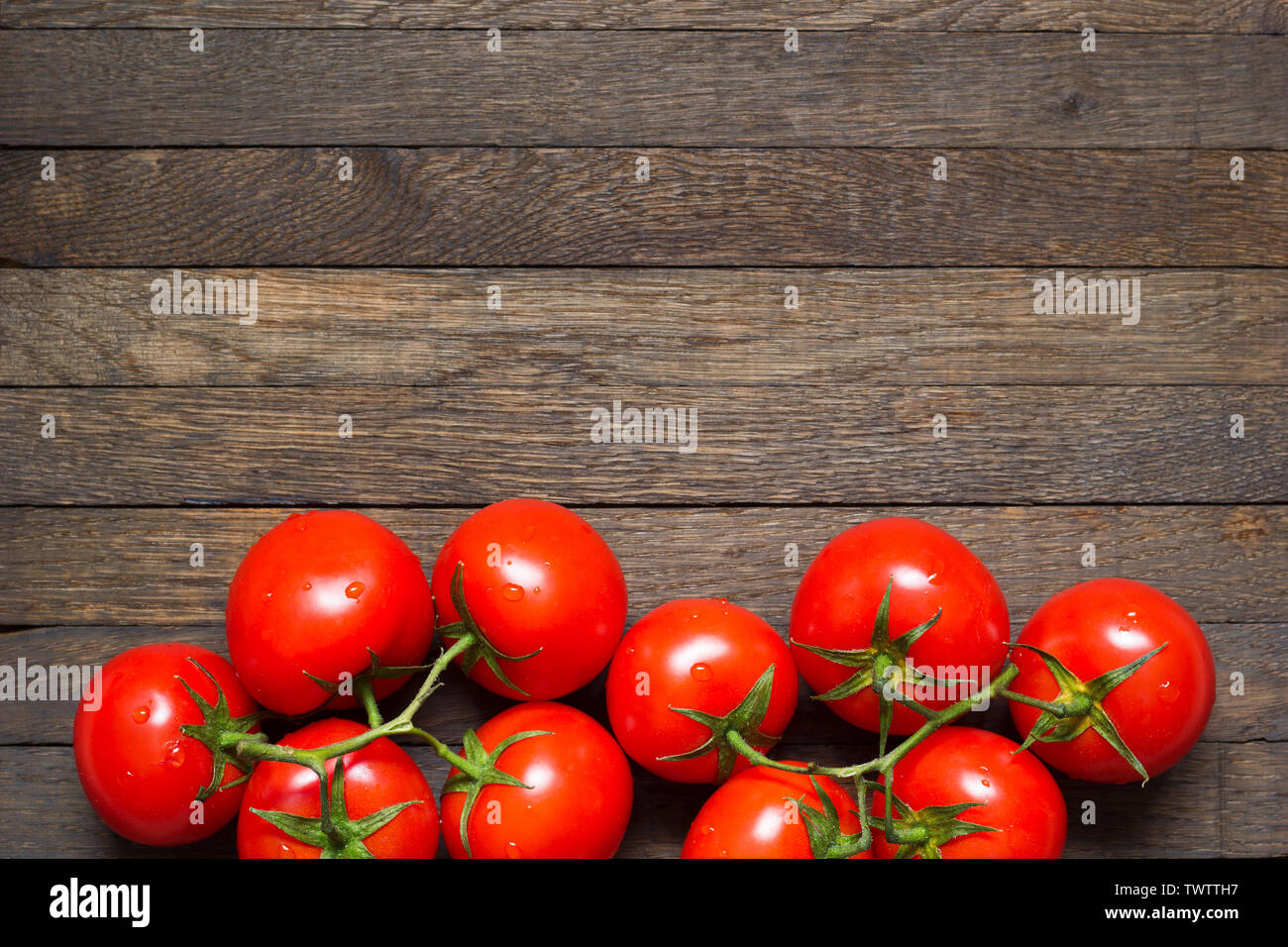 Red washed ripened tomatoes in bottom part of wooden background. Copy space on top. Water droplets on freshness vegetables. Top view. Close up. Health Stock Photo