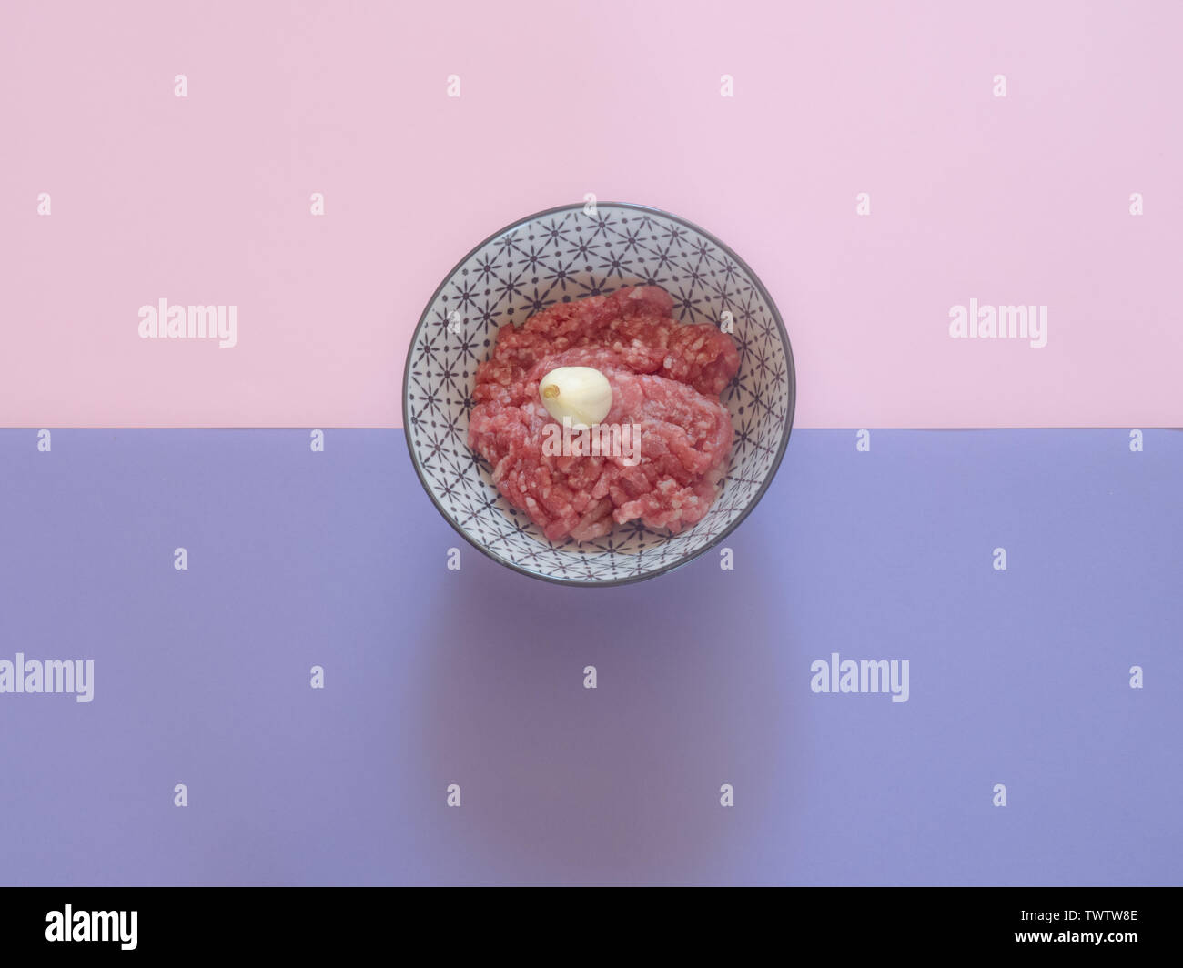 Minced beef meat in a bowl on pink and purple background Stock Photo