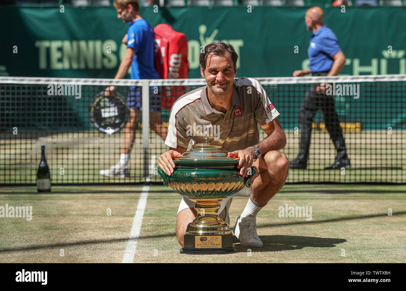 Halle, Germany. 23rd June, 2019. Tennis: ATP-Tour singles, men, final,  Federer (Switzerland) - Goffin (Belgium). The winner Roger Federer kneels  next to the trophy after the award ceremony. In the background the