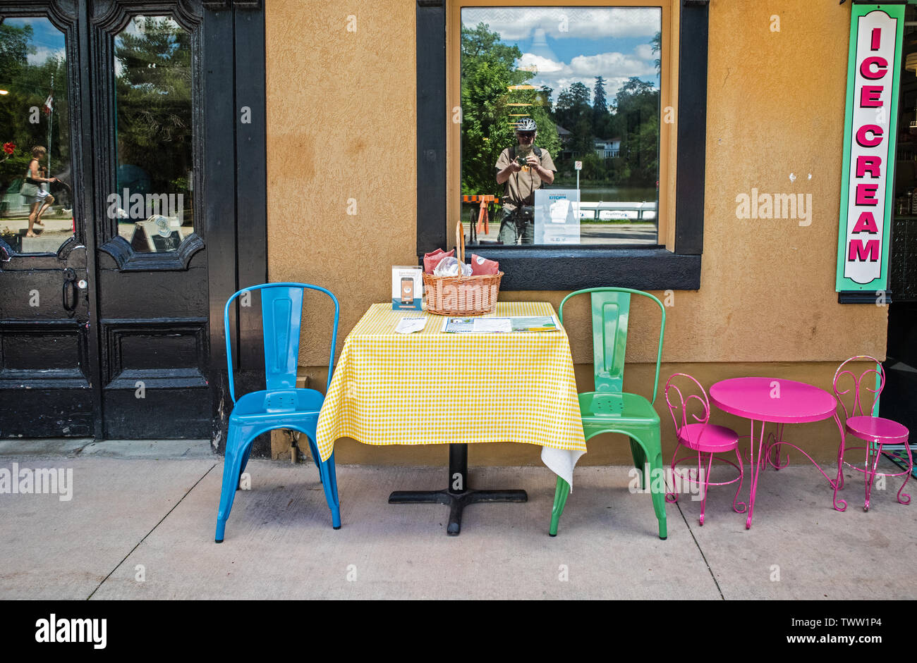 Outside, in the street, a table and chairs for adults, a table and chairs for children. A diary shop..the photographer is in the window reflexion.life Stock Photo
