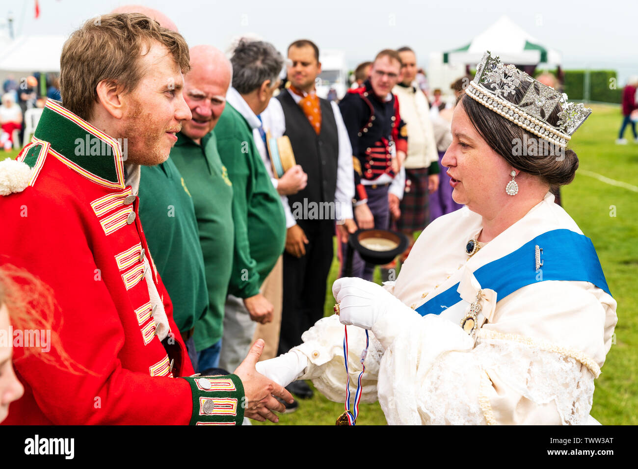 Broadstairs Dickens Festival. People dressed in Victorian Dickensian costume. Queen Victoria look-a-like shaking the hand of redcoat soldier who she is about to present with a medal. Close up. Stock Photo