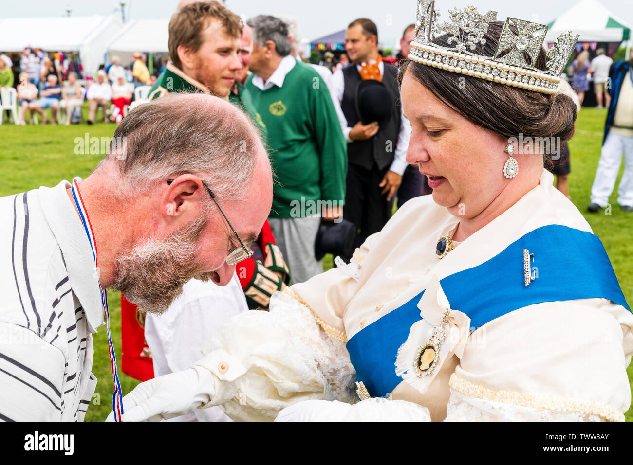 Broadstairs Dickens Festival. People dressed in Victorian Dickensian costume. Queen Victoria look-a-like at outdoor ceremony handing out medals to cricket players. Close up of her standing in front of man, who is bowing to her. Head and shoulders. Stock Photo