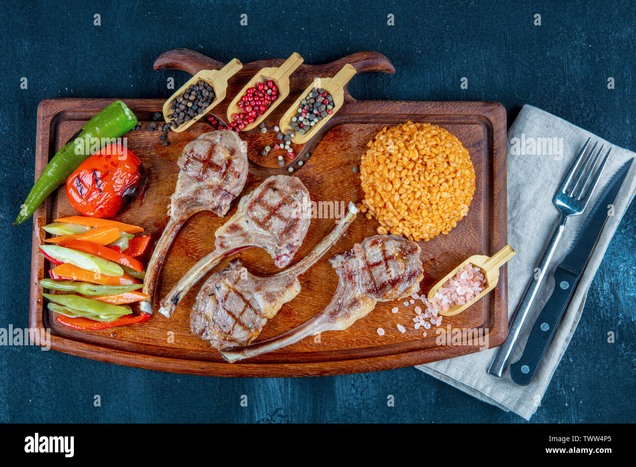 Lamb ribs grilled on cutting board with roasted vegetables. Top view Copy space Wooden background. Halal restaurant concept. Stock Photo