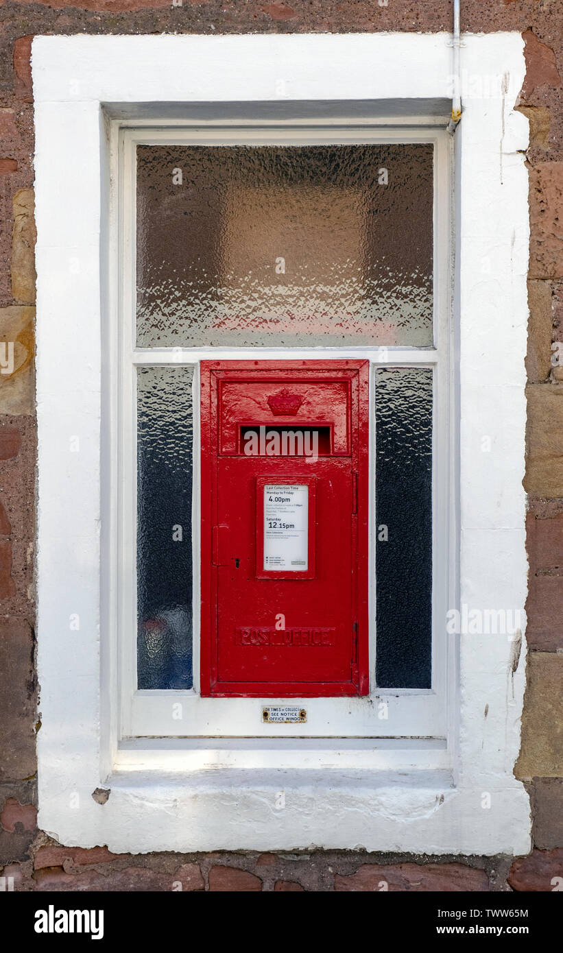 A red post box in a window with a white border in Cromarty, Black Isle, Ross and Cromarty, Scotland, United Kingdom. Stock Photo