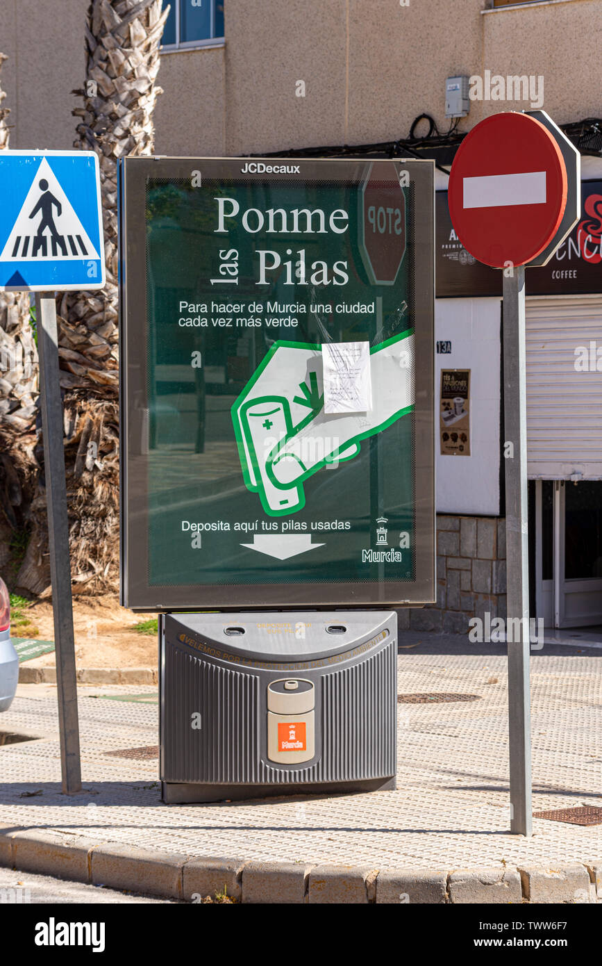 Battery recycling deposit bin in Sucina, Murcia, Spain, Europe. Ponme las Pilas. Spanish street scene with no entry and crossing road signs. Bin Stock Photo