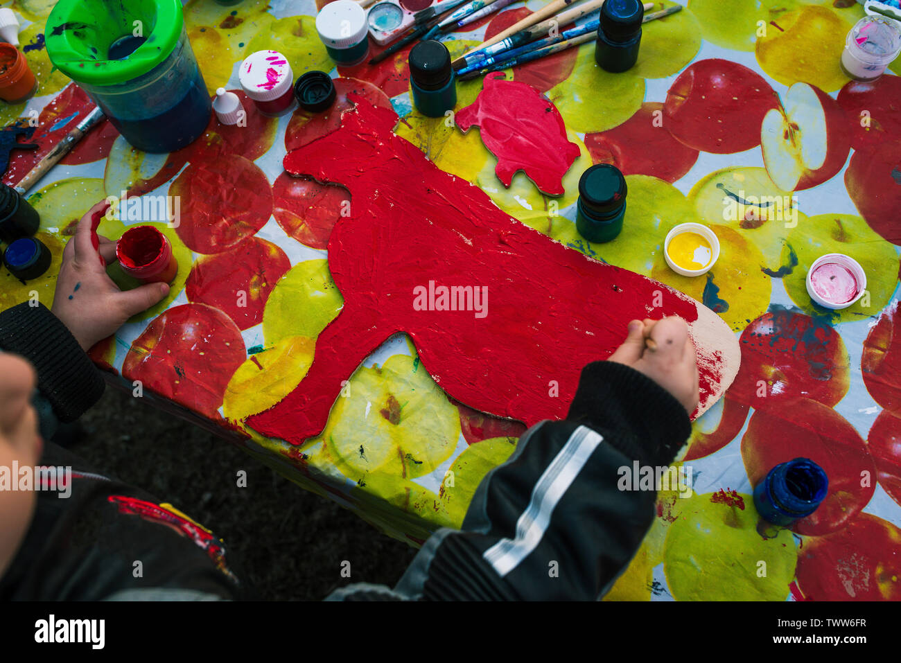 Russia, Yaroslavl city - May 4, 2019:Baby girl draws on the wooden board. The child holds the brush. Around there are paints and cans of water. The Stock Photo