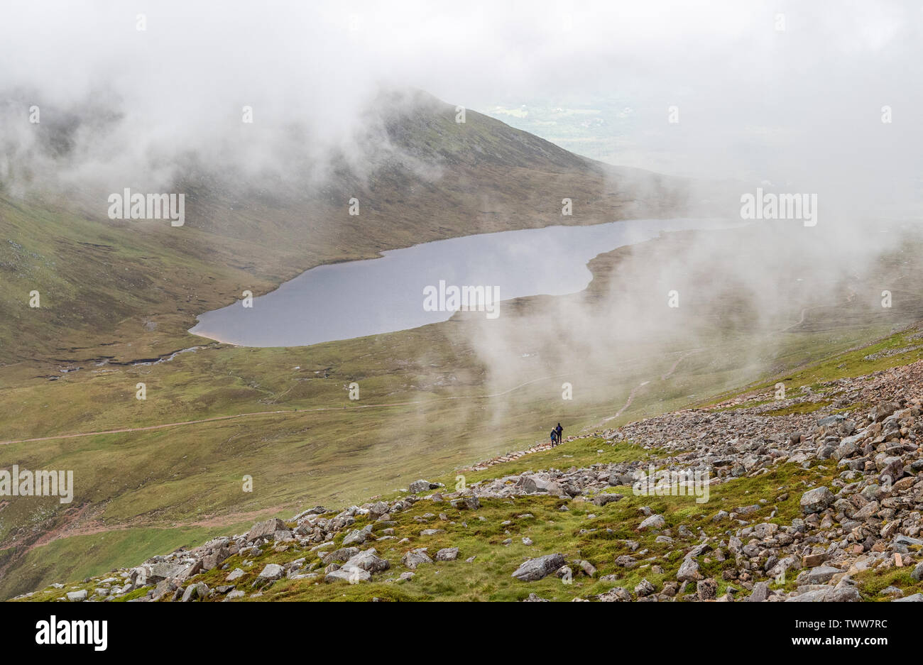 Walkers looking out over Lochan Meall on the ascent to the summit of Ben Nevis in the Highlands of Scotland UK on a typically cloudy day Stock Photo