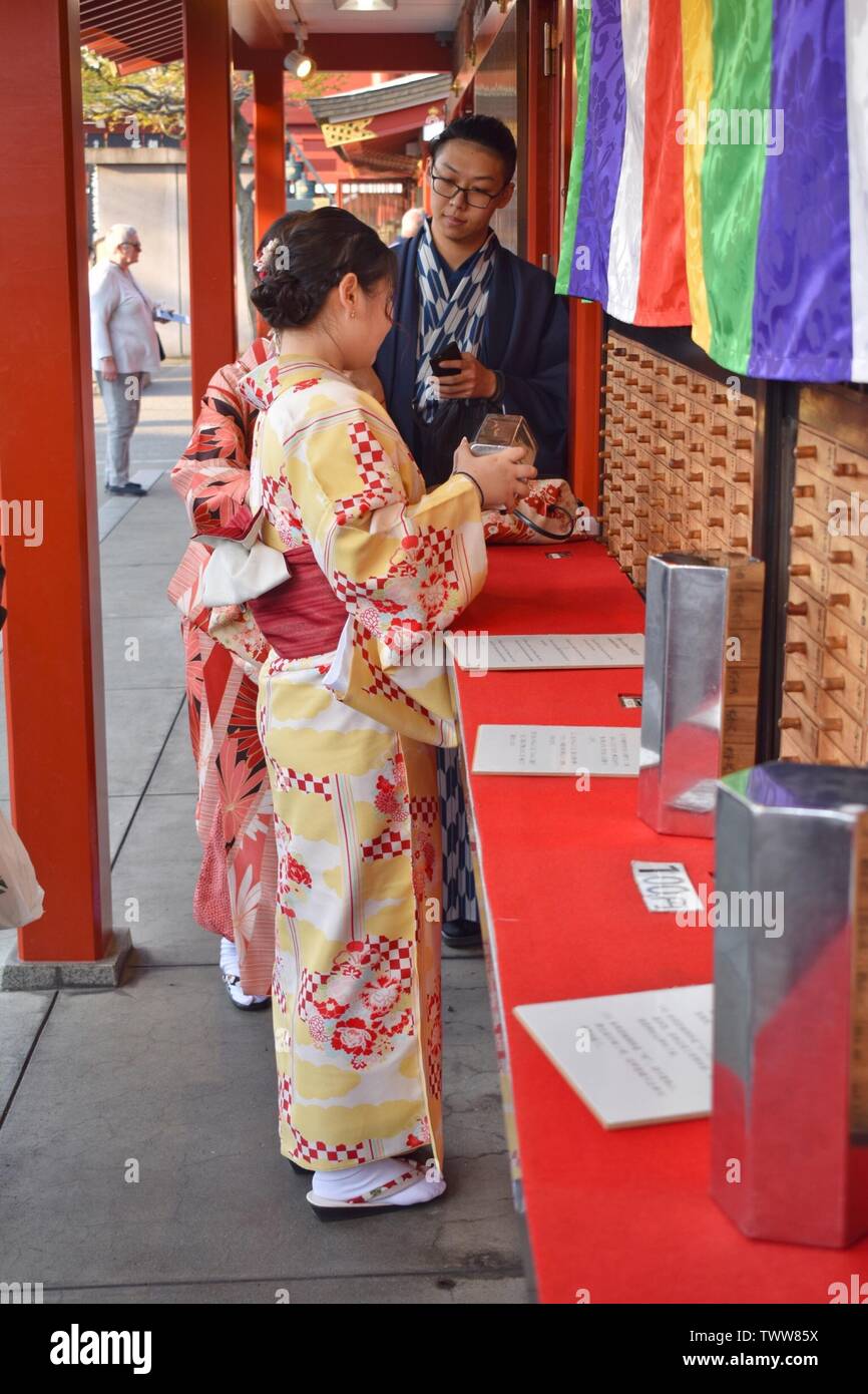 Girls and boy dressed in traditional Japanese dress with traditional paper prophecy Omikudži for knowing their future, Sensó-ji temple, Tokyo, Japan Stock Photo
