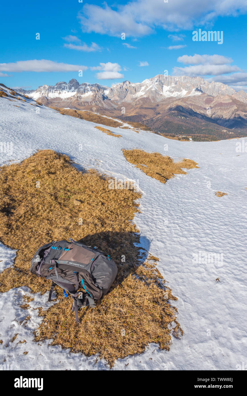 Hiker's backpack left in the snow after a long hike in the Dolomites. Autumn in the mountains, fall colours in the alpine. McKinley grey backpack. Stock Photo