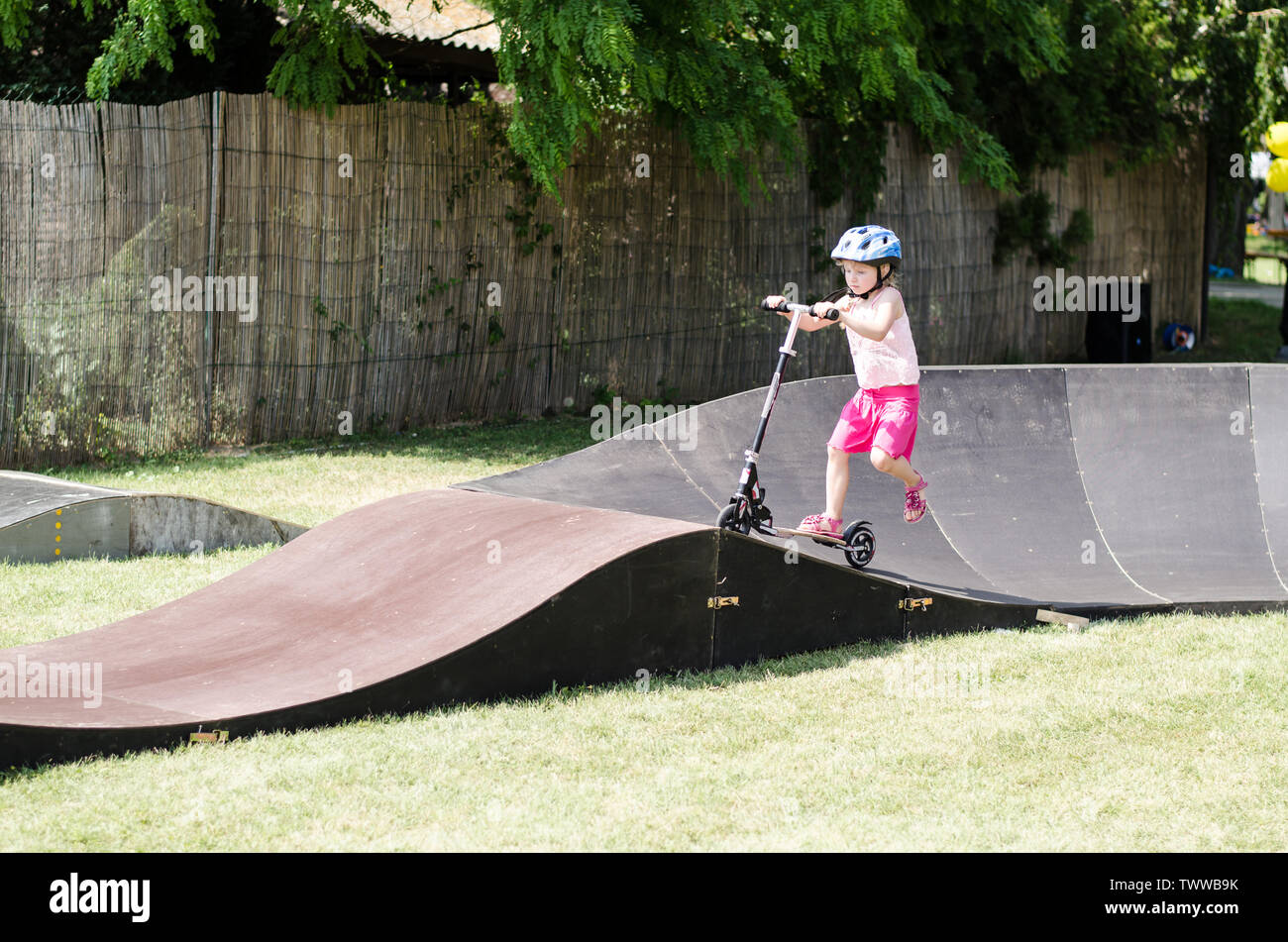 little girl with helmet riding a scooter in ramp Stock Photo - Alamy