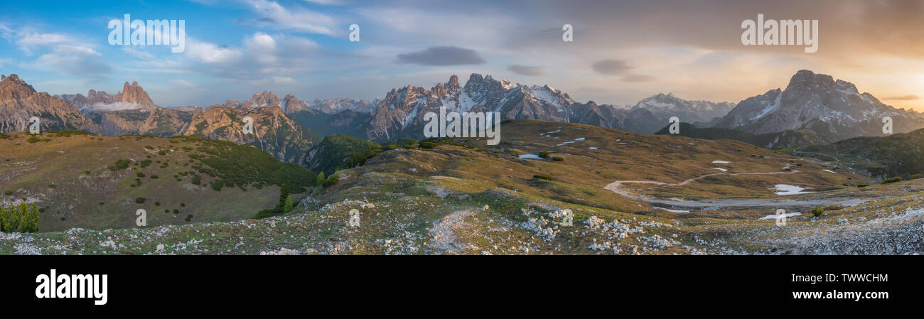 Panoramic view of the Italian Dolomites during a colorful sunset, sky ablaze with colours. Twilight with alpenglow, Cristallo and Tre Cime at sunset. Stock Photo