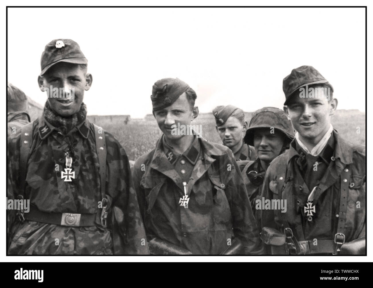 WW2 WAFFEN SS IRON CROSS MEDALS Nazi Propaganda image of young German Waffen SS men displaying newly awarded Iron Cross Medals in the field On the invasion front near Caen Three young men of the Waffen-SS after the award of the Iron Cross II 1944 Caen France Stock Photo