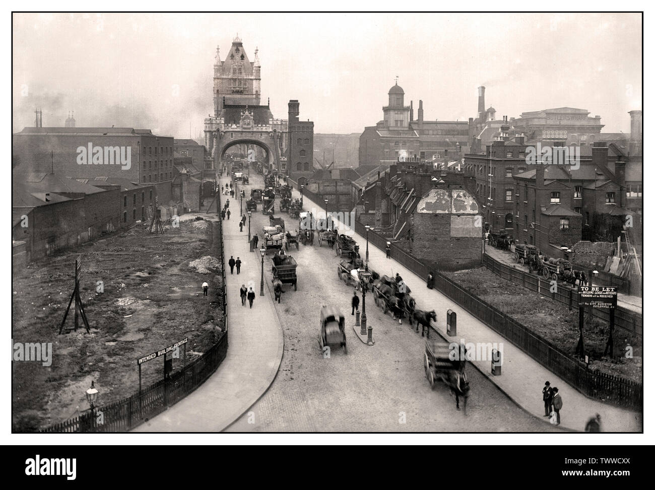 LONDON VINTAGE HISTORIC TOWER BRIDGE ROAD Vintage 1900’s Victorian era B&W image of Tower Bridge and area showing a variety of horse drawn carriages and industrial commercial transportations London UK Stock Photo