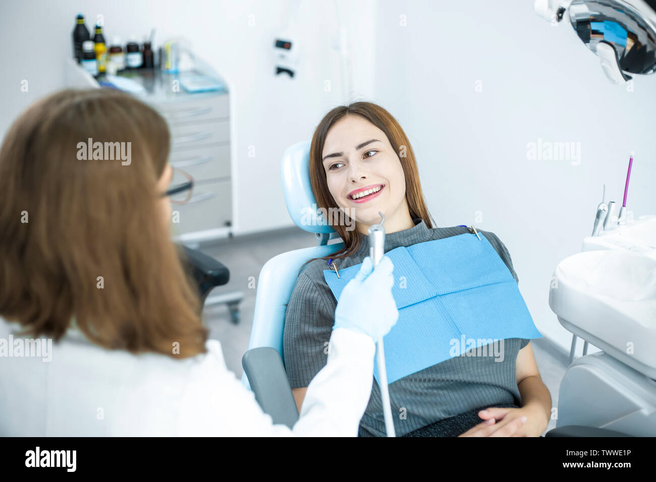 Smiling girl treats teeth while sitting in the dental chair at the doctor. Stock Photo