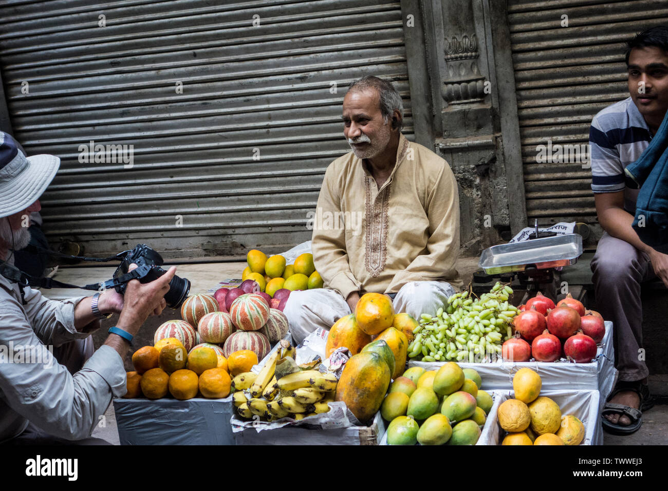 Market vendor of fruit and vegetables having his photograph taken by a tourist in Old Delhi, New Delhi, India Stock Photo