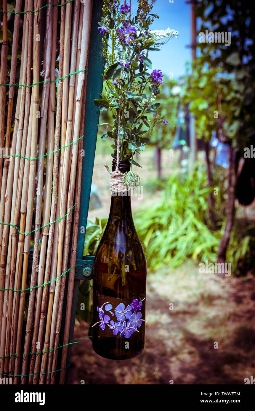 flowers in glass bottle hanged over wooden fence Stock Photo