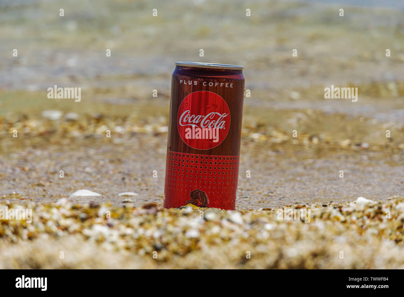 Coca Cola Plus Coffee 330 ml can on sand by the sea. New soft sugarless drink with more caffeine than a Coke Classic, partly submerged on sandy beach Stock Photo