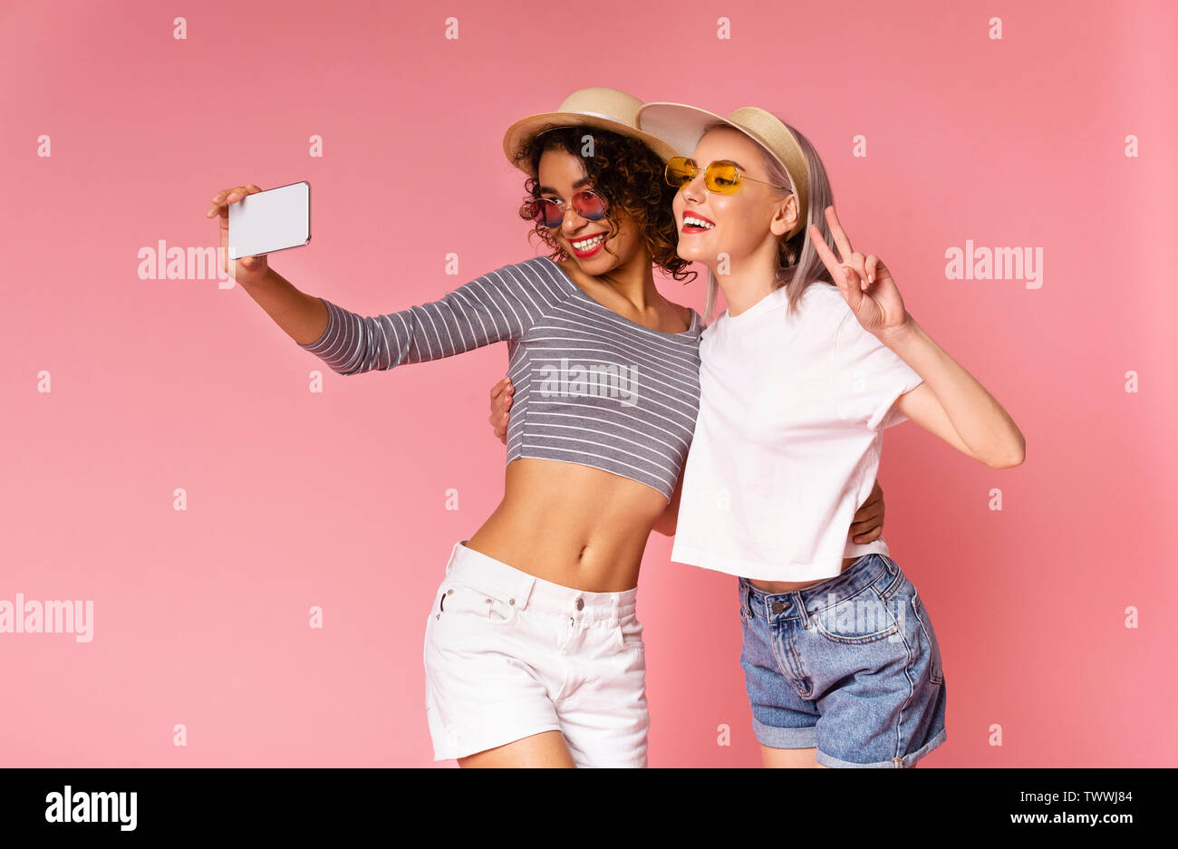 Two cheerful young diverse women taking selfie on smartphone Stock Photo