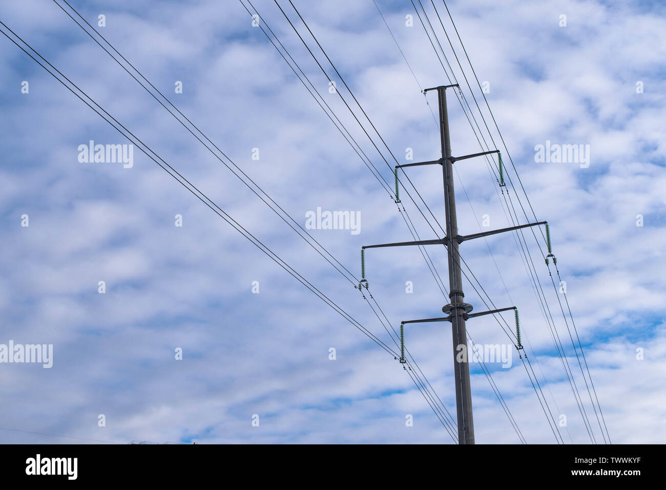 power line tower on a cloudy blue sky background Stock Photo - Alamy