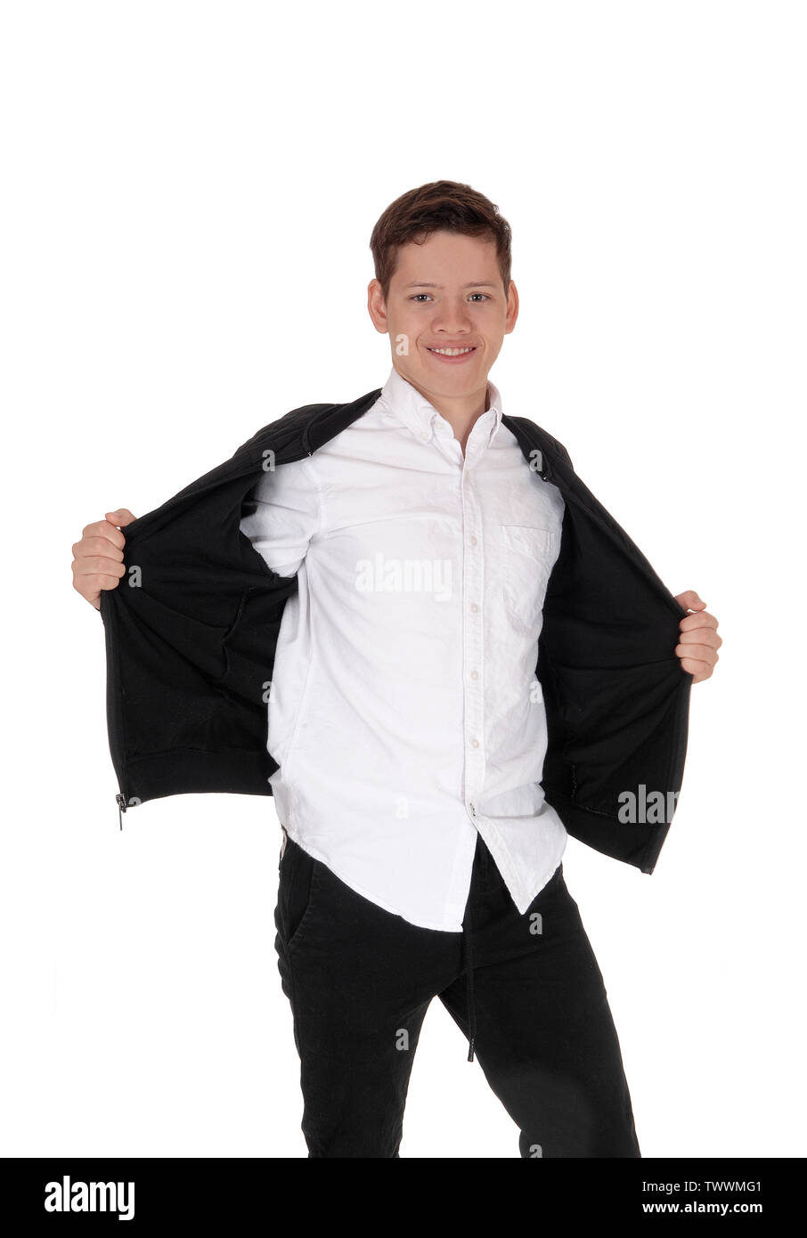 A lovely young teenager boy standing in the studio, smiling, holding his black jacket open, whit a white shirt, isolated for white background Stock Photo