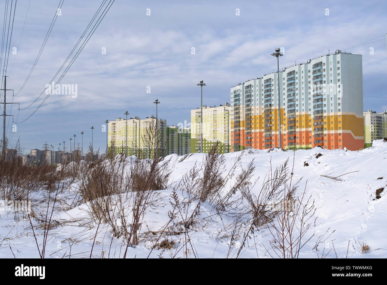 residential high-rise buildings on the background of dirty snowy hills Stock Photo