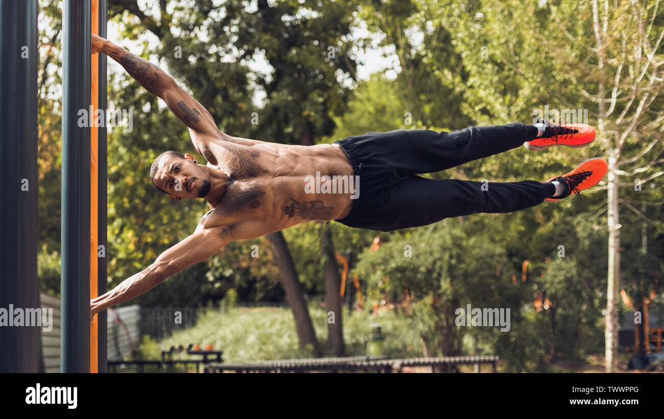 Strong Man Practicing Human Flag Exercise, Gripping Vertical Bar Stock Photo