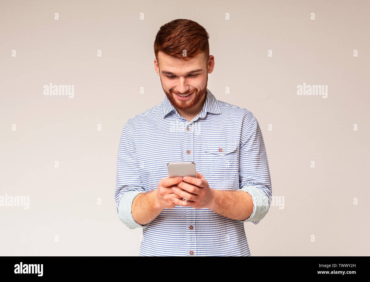 Young man absorbedly text messaging on his cellphone Stock Photo