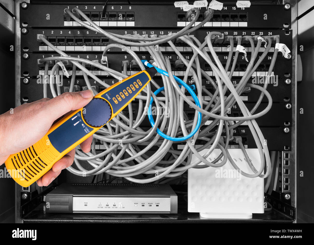 Network cable tester detail. Measuring probe in hand of expert. Diagnostic measurement of structured cabling in patch panels of rack case. IT service. Stock Photo