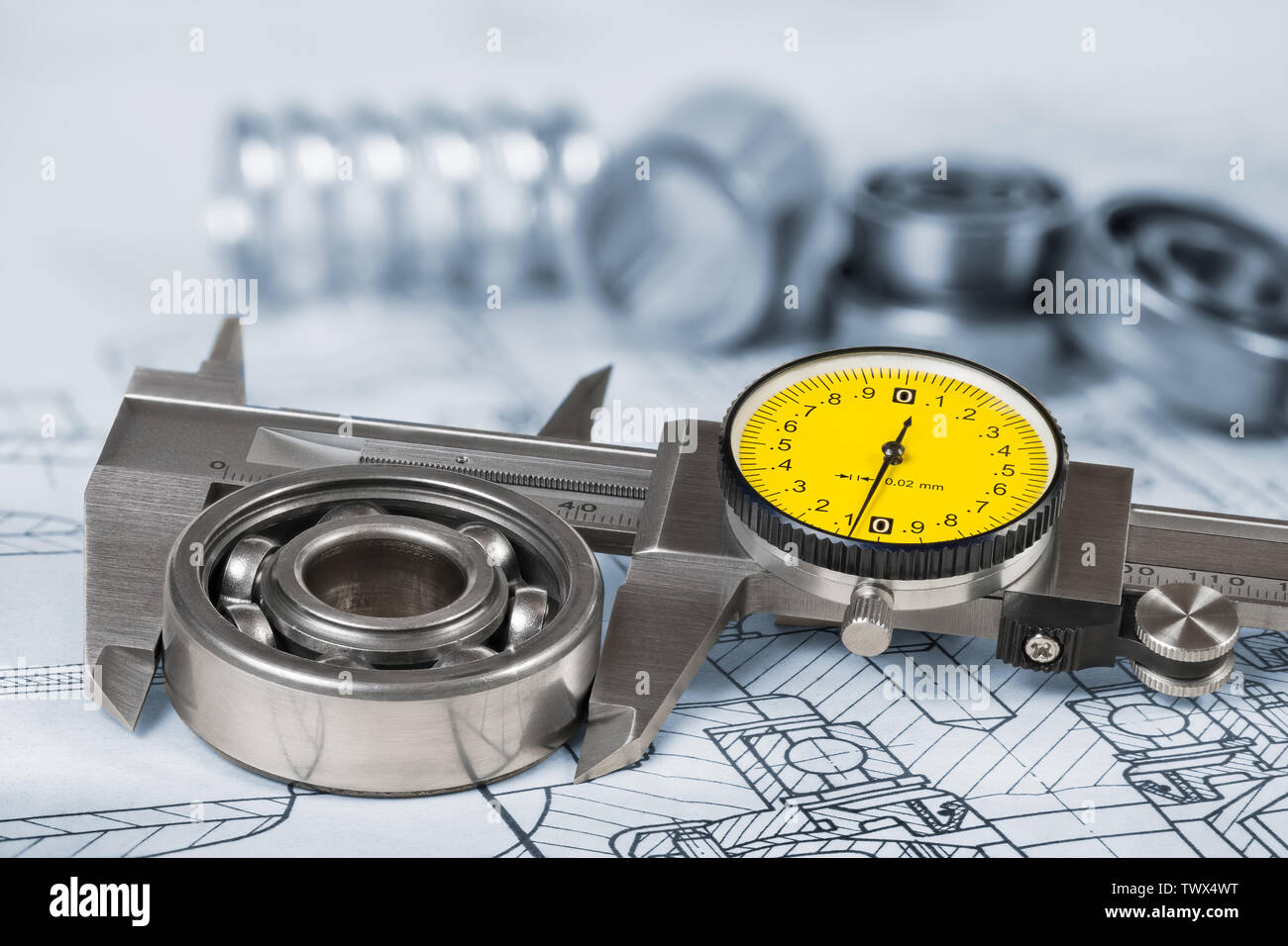 Ball bearing diameter measurement. Caliper gauge on technical drawing. Accurate measuring tool. Vernier scale, yellow round dial, group of steel parts. Stock Photo