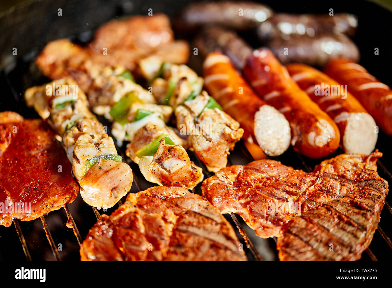 Different types of juicy meats on hot coals on grill in garden Stock Photo