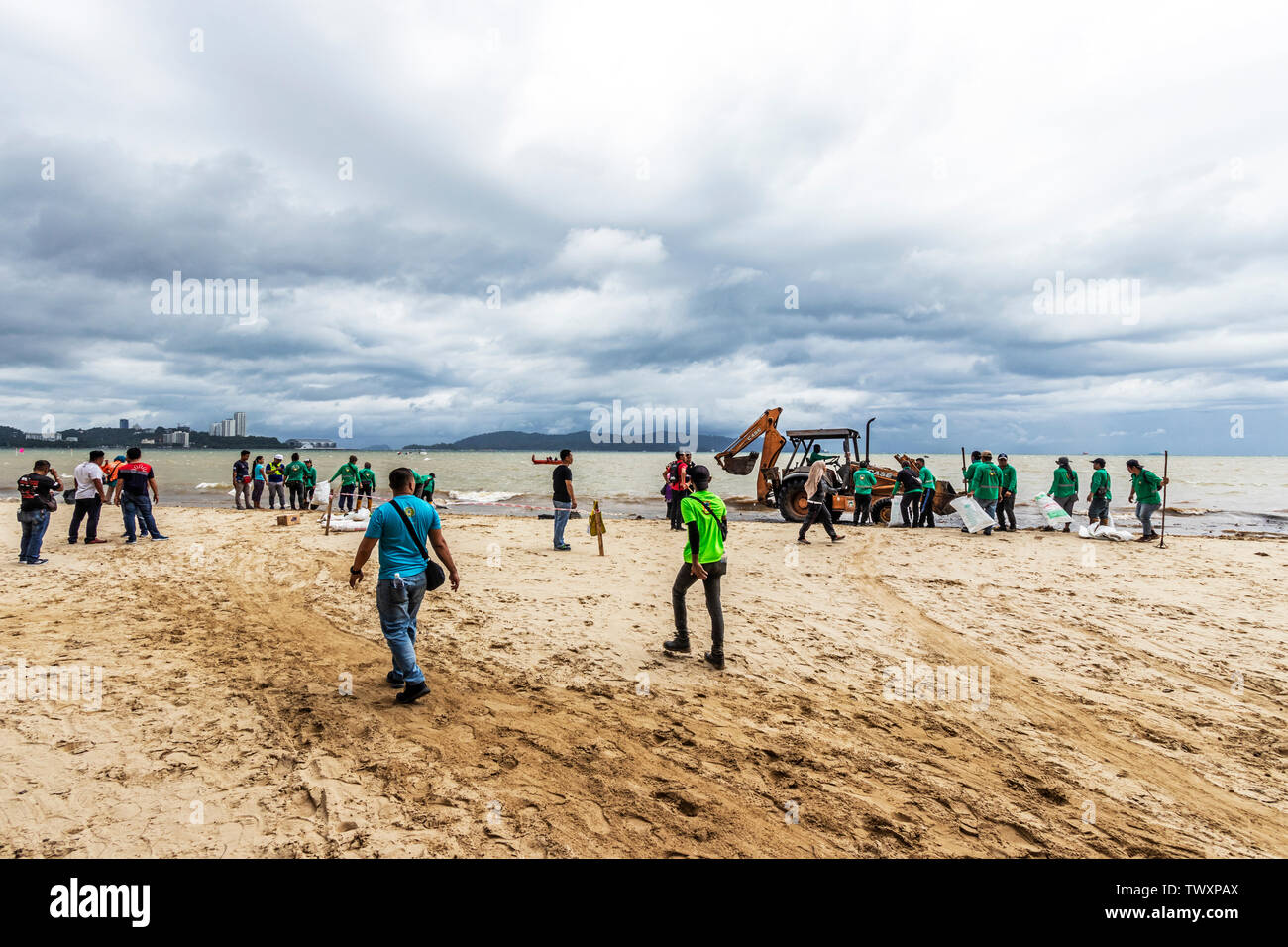 Workers cleaning up the beach at Likas Bay Kota Kinabalu Sabah Malaysia