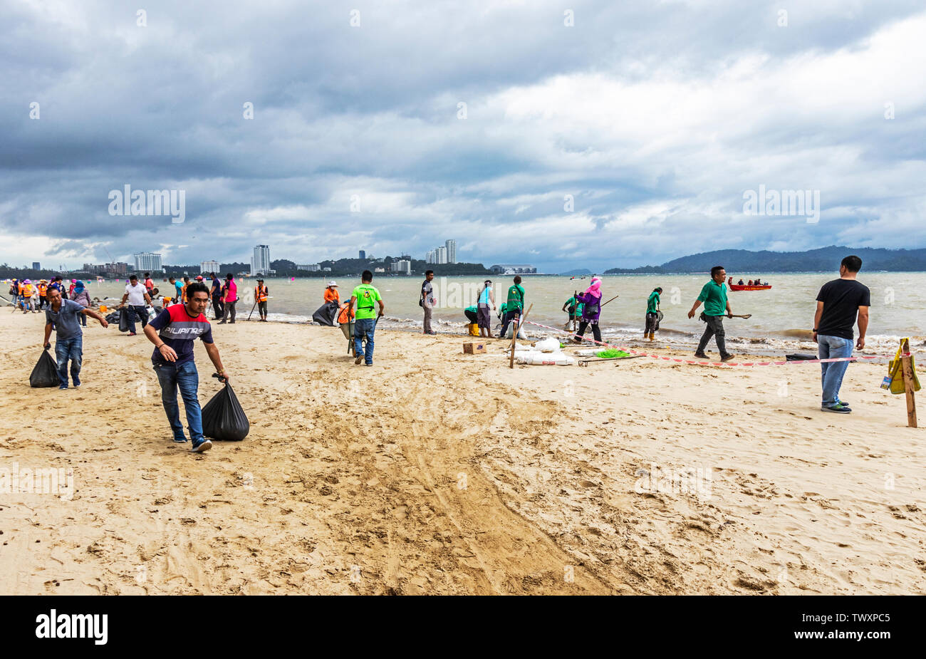 Workers cleaning up the beach at Likas Bay Kota Kinabalu Sabah Malaysia