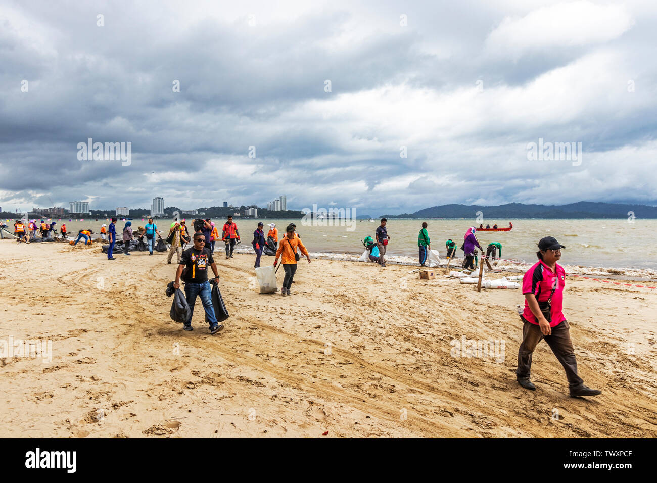 Workers cleaning up the beach at Likas Bay Kota Kinabalu Sabah Malaysia