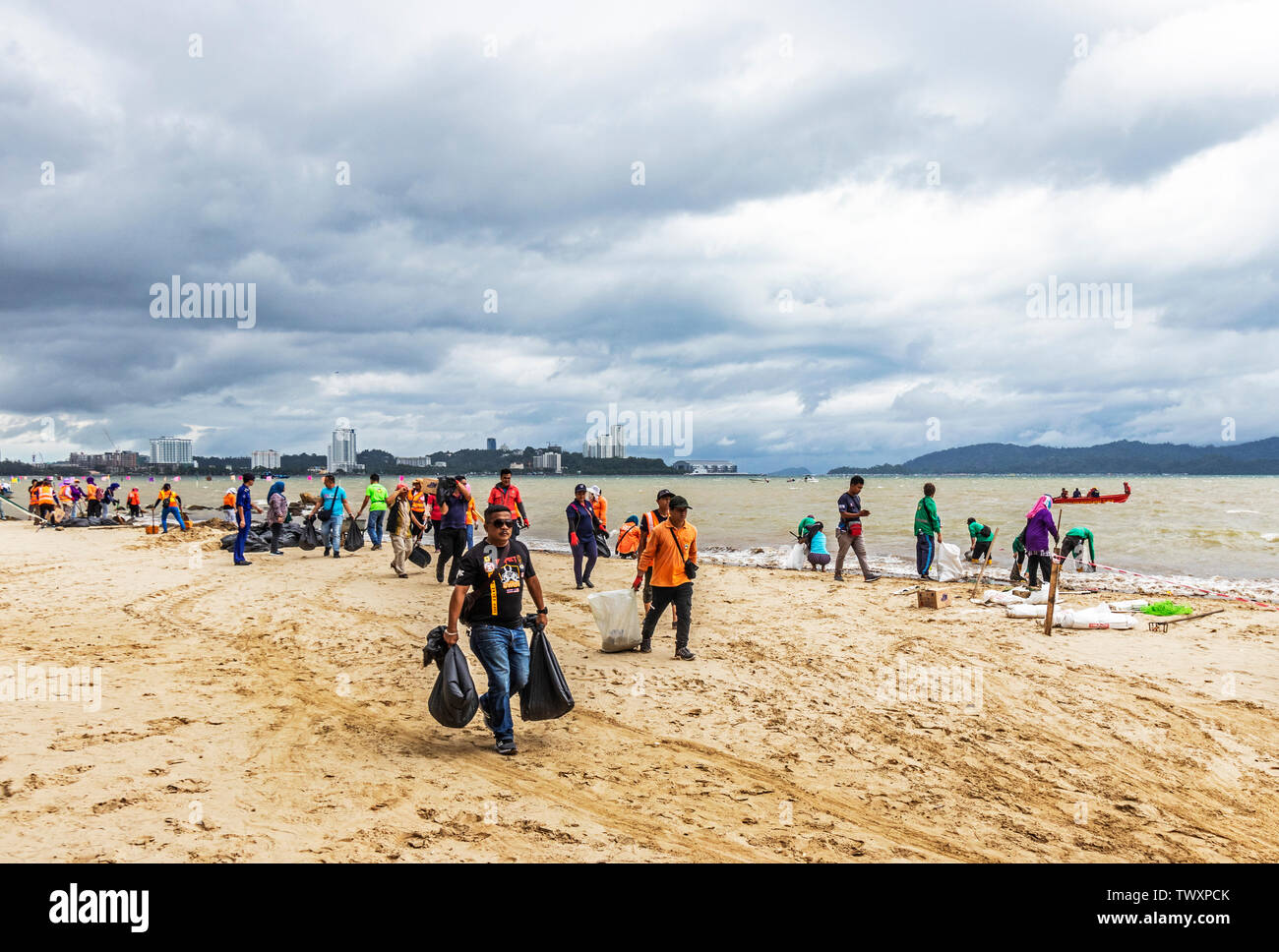 Workers cleaning up the beach at Likas Bay Kota Kinabalu Sabah Malaysia