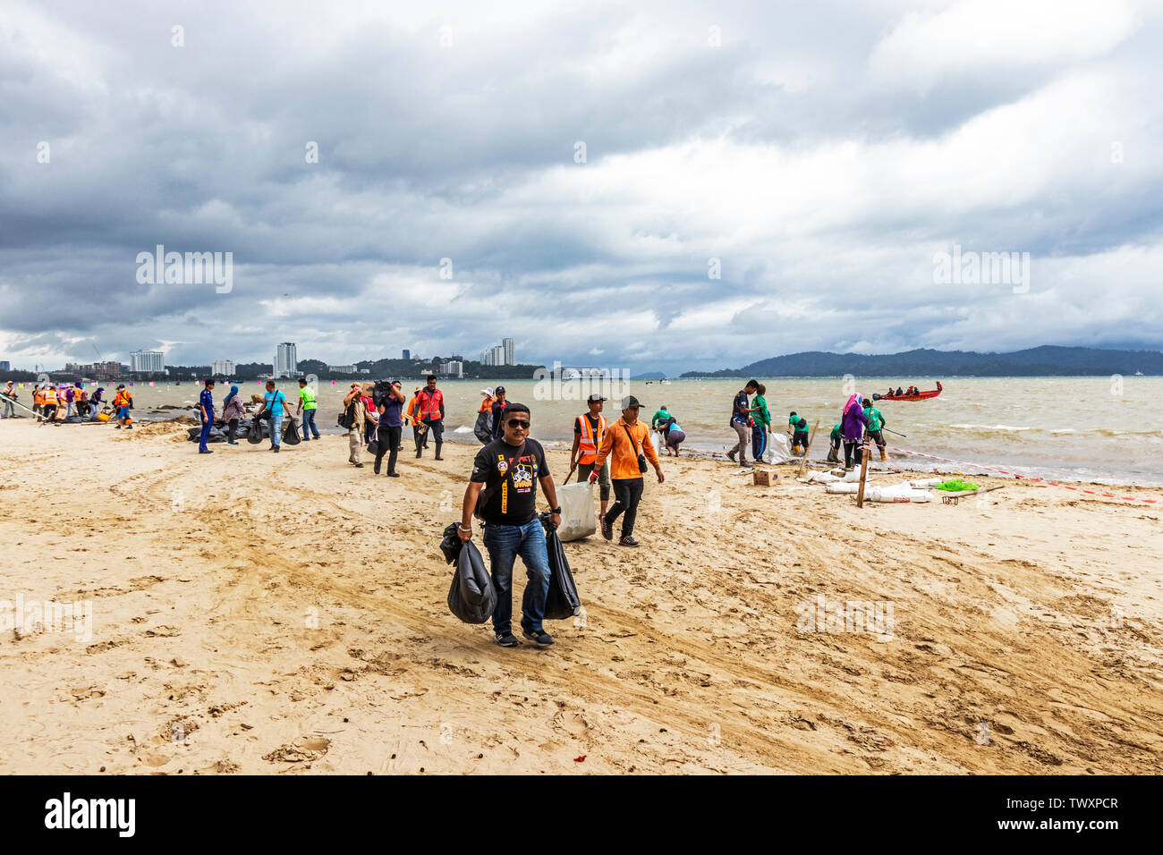 Workers cleaning up the beach at Likas Bay Kota Kinabalu Sabah Malaysia
