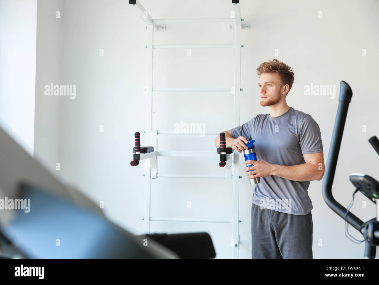 Sporty young man with bottle of water in gym Stock Photo - Alamy