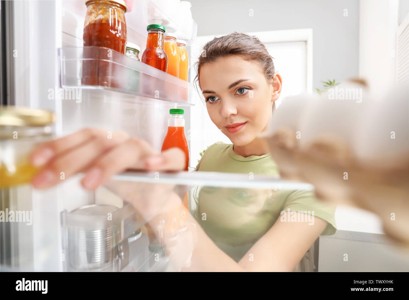 Woman taking food out of fridge at home, view from inside Stock Photo