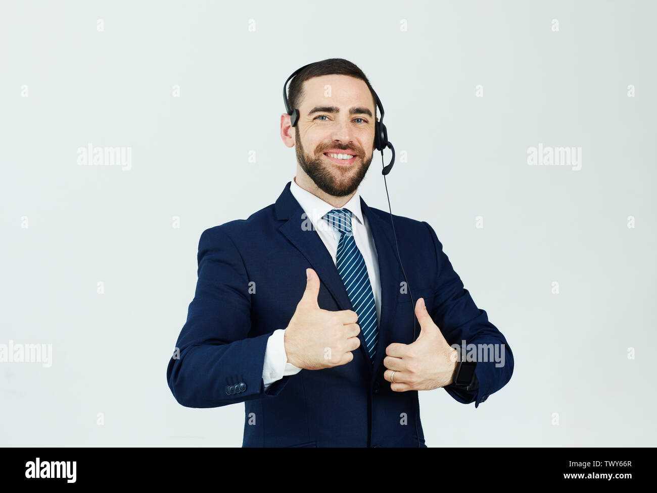 Portrait of cheerful confident handsome young male support operator in headset showing thumbs-up Stock Photo