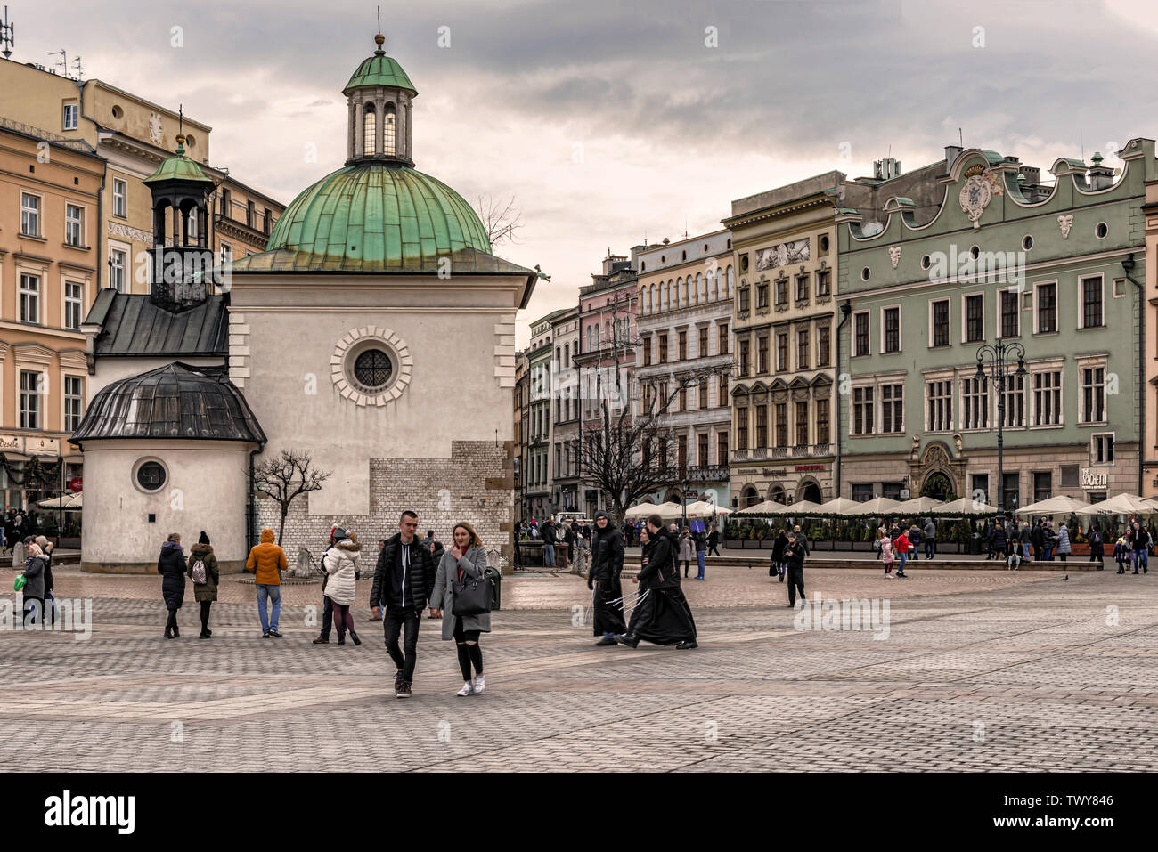 Cracow, Poland – Feb 2, 2019: Tourists at main square passing by The Church of St. Adalbert or of St. Wojciech, the 11th century church in Cracow, Pol Stock Photo