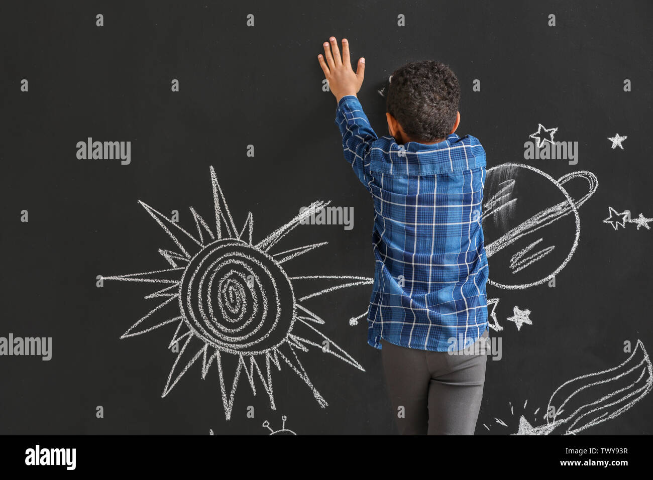 Cute African-American boy drawing space on dark wall Stock Photo