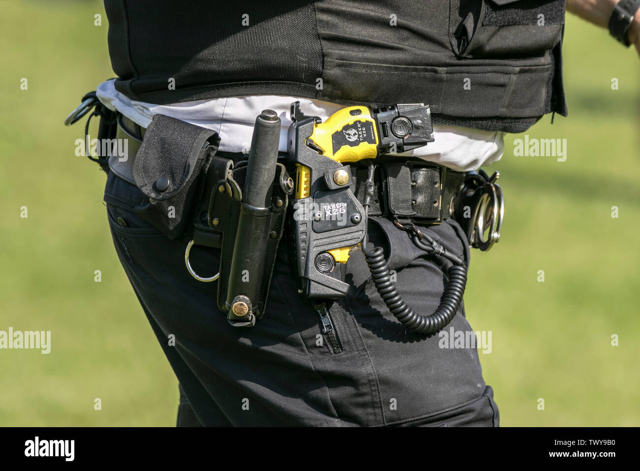 A UK armed police officer wearing a Taser stun gun as standard protective equipment to deter criminal from attacking police officers Stock Photo