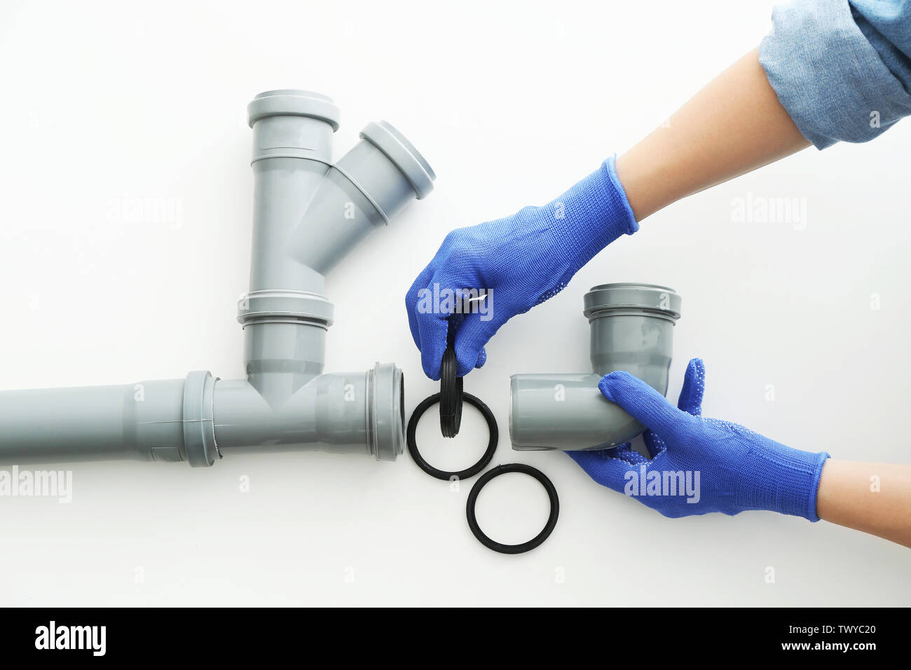 Plumber working with drain pipe on white background Stock Photo