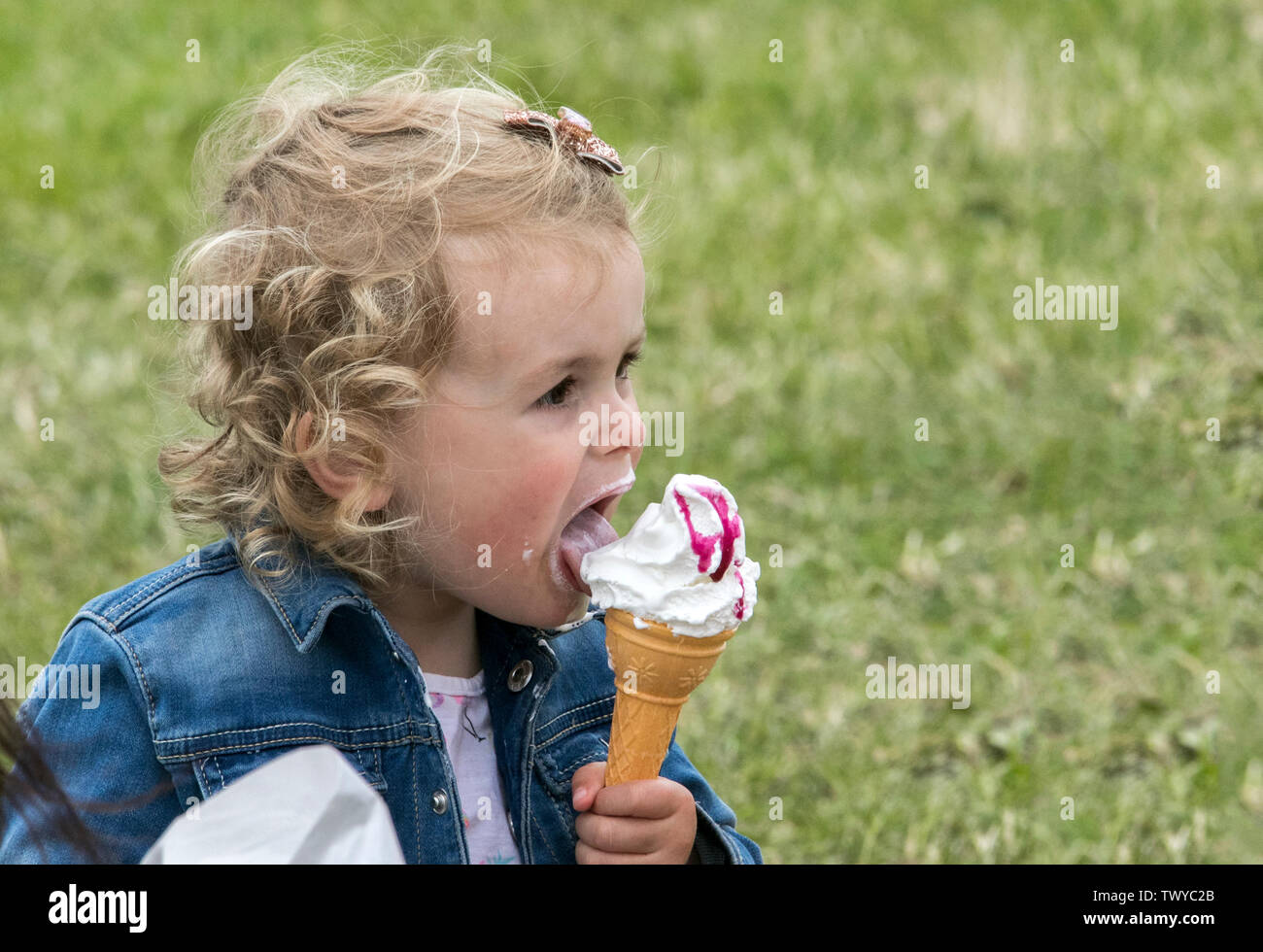 A young infant girl enjoys a delicious ice cream on a summer day Stock Photo