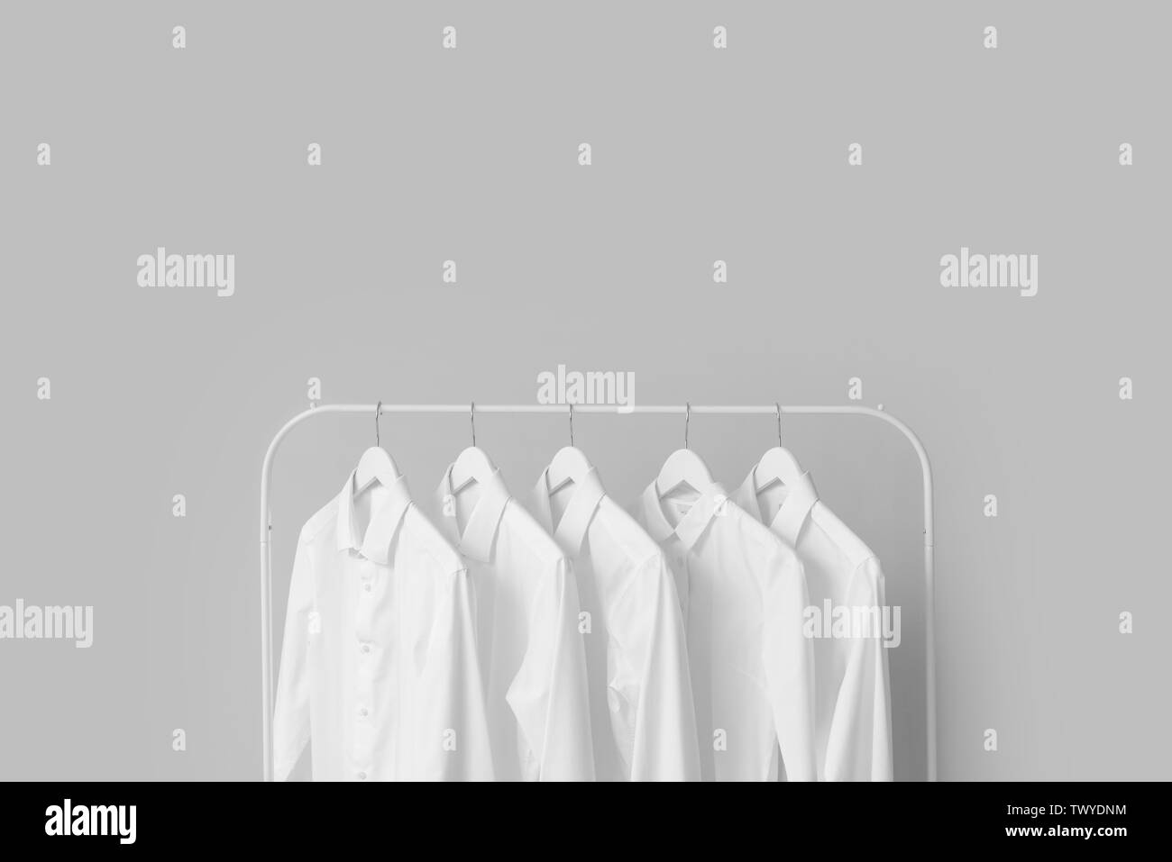 Rack with clothes after dry-cleaning on light background Stock Photo