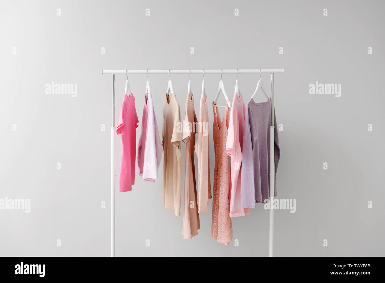 Rack with clothes after dry-cleaning on light background Stock Photo
