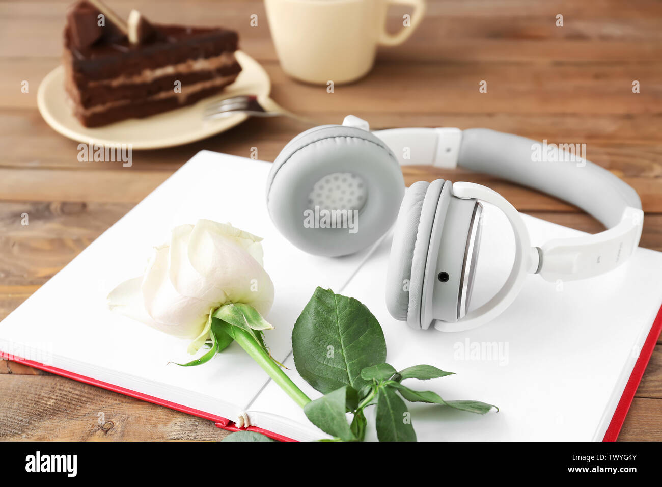 Open book, flower, cup of coffee and cake on wooden background. Concept of audiobook Stock Photo