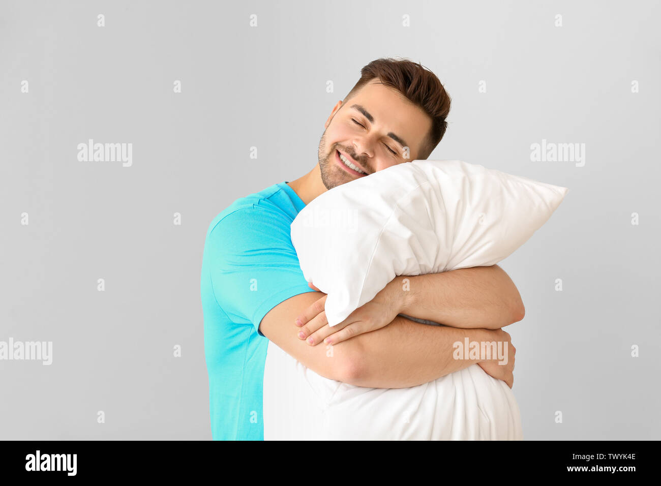 Handsome man hugging pillow against white background Stock Photo Alamy