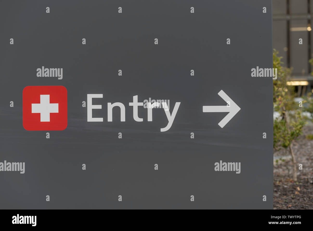 Beside a white cross on red background the word Entry and a white arrow pointing right at a hospital in Sydney, Australia Stock Photo